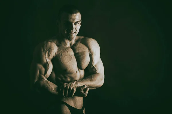 Bodybuilder sur fond sombre . — Photo