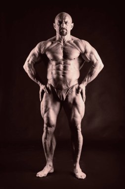 Karanlık bir arka plan üzerinde güçlü kas adam.