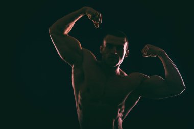 Karanlık bir arka plan üzerinde güzel vücut geliştirmeci siluet.