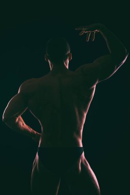 Karanlık bir arka plan üzerinde güzel vücut geliştirmeci siluet.