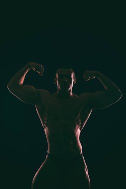 Karanlık bir arka plan üzerinde güzel vücut geliştirmeci siluet.