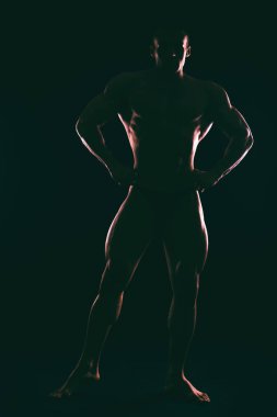 Karanlık bir arka plan üzerinde güzel vücut geliştirmeci siluet.