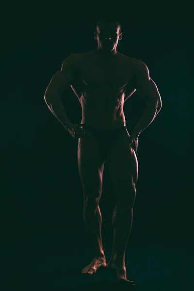 Silhouette schöner Bodybuilder auf dunklem Hintergrund. — Stockfoto