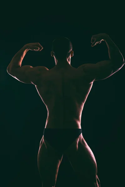 Karanlık bir arka plan üzerinde güzel vücut geliştirmeci siluet. — Stok fotoğraf