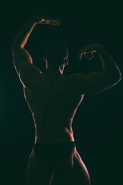 Silhouette schöner Bodybuilder auf dunklem Hintergrund. — Stockfoto