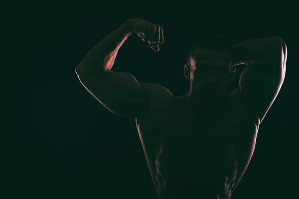 Silhouette magnifique bodybuilder sur un fond sombre . — Photo