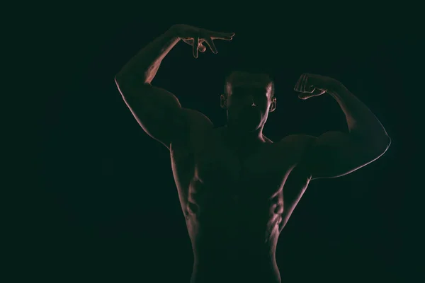 Silhouet van mooie bodybuilder op een donkere achtergrond. — Stockfoto