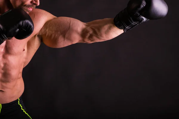 Sterke gespierde man op een donkere achtergrond. — Stockfoto