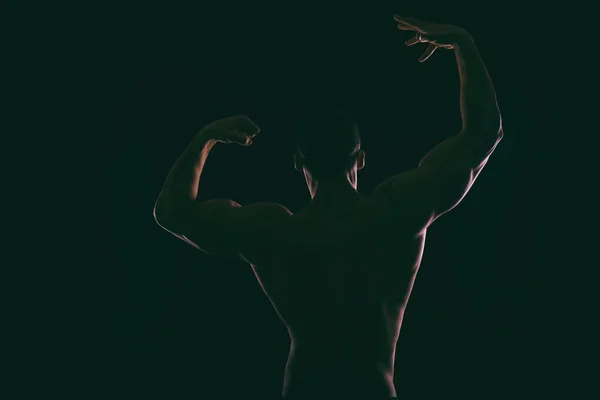 Silhouette schöner Bodybuilder auf dunklem Hintergrund. — Stockfoto