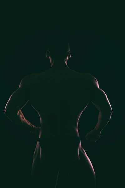 Silhouette magnifique bodybuilder sur un fond sombre . — Photo