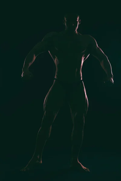 Σιλουέτα όμορφη bodybuilder σε σκούρο φόντο. — Φωτογραφία Αρχείου