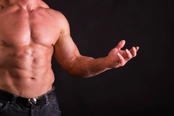 Forte bodybuilder posa su uno sfondo scuro . — Foto Stock