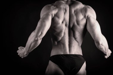 Bir adam siyah bir zemin üzerine muhteşem bir kas vücut ile