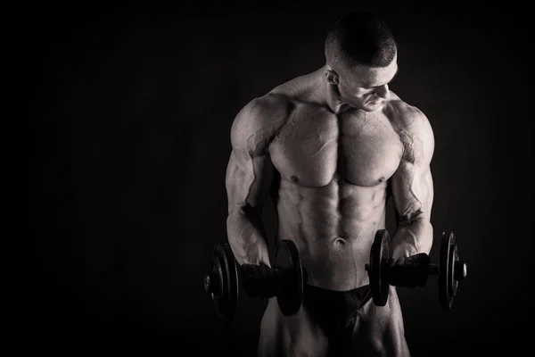 Ein Mann mit einem wunderschönen muskulösen Körper auf schwarzem Hintergrund — Stockfoto