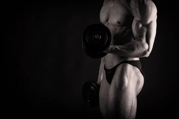 Un hombre con un cuerpo musculoso magnífico sobre un fondo negro — Foto de Stock