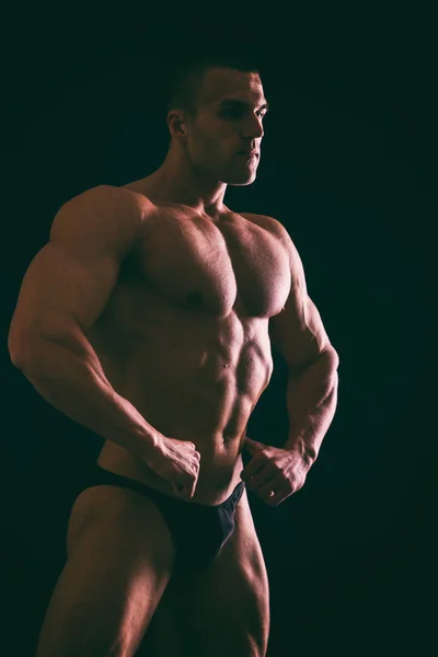 Cuerpo masculino muscular sobre un fondo oscuro . — Foto de Stock