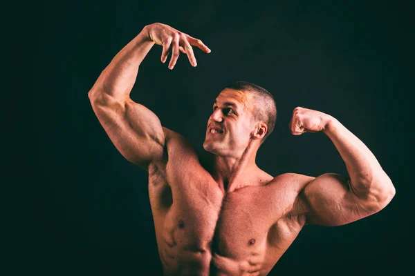 Corpo masculino muscular em um fundo escuro . — Fotografia de Stock