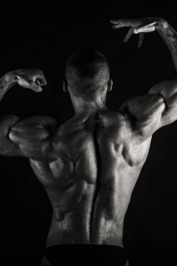 Bir adam siyah bir zemin üzerine muhteşem bir kas vücut ile