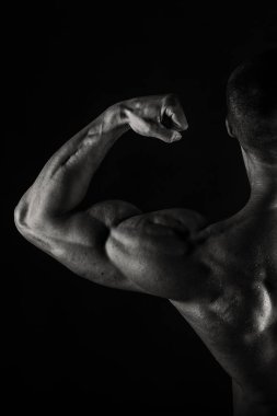 Bir adam siyah bir zemin üzerine muhteşem bir kas vücut ile