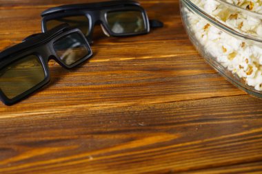 Gevşek patlamış mısır ve ahşap arka plan üzerinde 3d gözlük