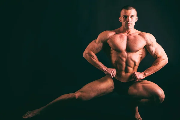 Muscoloso corpo maschile su uno sfondo scuro . — Foto Stock