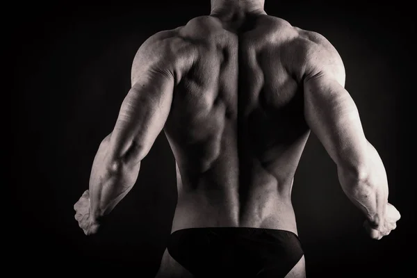 Un uomo con un corpo muscoloso splendido su uno sfondo nero — Foto Stock