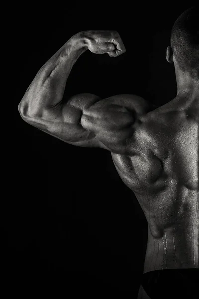 Een man met een schitterende gespierd lichaam op een zwarte achtergrond — Stockfoto