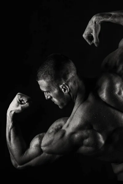 Un hombre con un cuerpo musculoso magnífico sobre un fondo negro —  Fotos de Stock