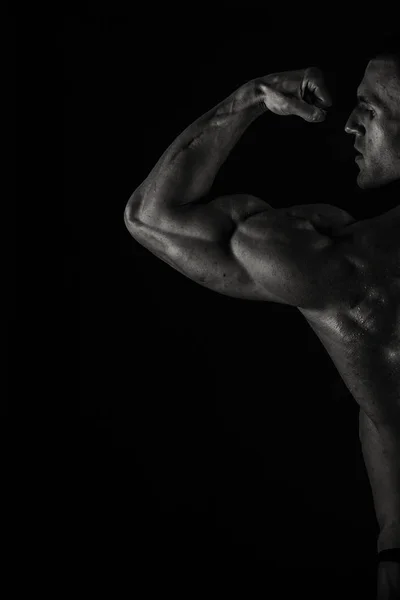 Un hombre con un cuerpo musculoso magnífico sobre un fondo negro — Foto de Stock