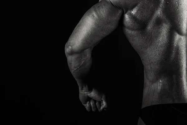 Un hombre con un cuerpo musculoso magnífico sobre un fondo negro — Foto de Stock