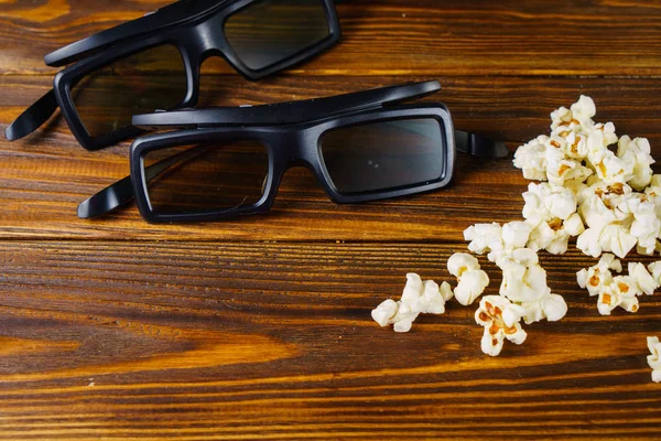 Popcorn sciolti e occhiali 3D su uno sfondo di legno — Foto Stock