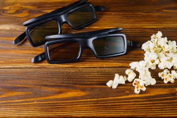 Loose popcorn and 3D glasses on a wooden background — Stock Photo, Image