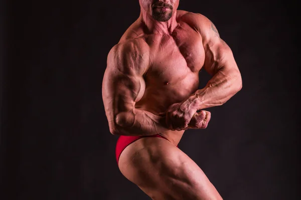 Bodybuilder poserar på en mörk bakgrund. — Stockfoto