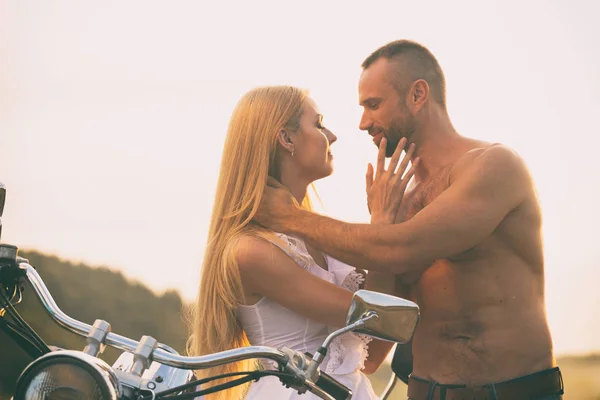 Loving couple on a motorcycle in a field — Stock Photo, Image