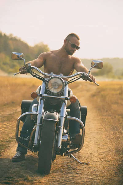 Macho em uma motocicleta em um campo — Fotografia de Stock