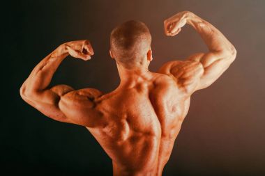 Karanlık bir arka plan üzerinde vücut geliştirmeci.