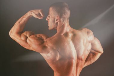 Karanlık bir arka plan üzerinde vücut geliştirmeci.