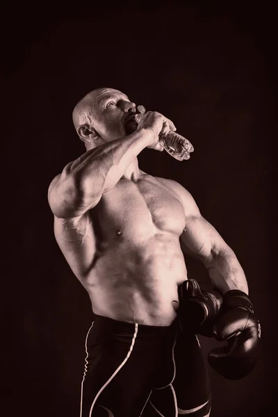 Kulturysta pozowanie w różnych pozach, wykazując ich mięśni. Awaria na ciemnym tle. Napinanie mięśni mężczyzna wyświetlone. Muskularne ciało sportowca. — Zdjęcie stockowe