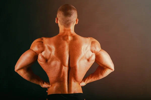 Bodybuilder op een donkere achtergrond. — Stockfoto