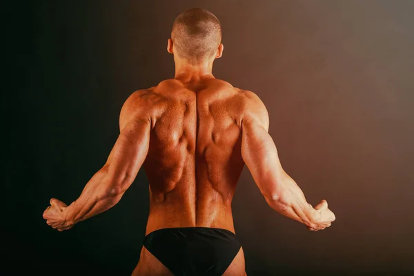 Bodybuilder op een donkere achtergrond. — Stockfoto