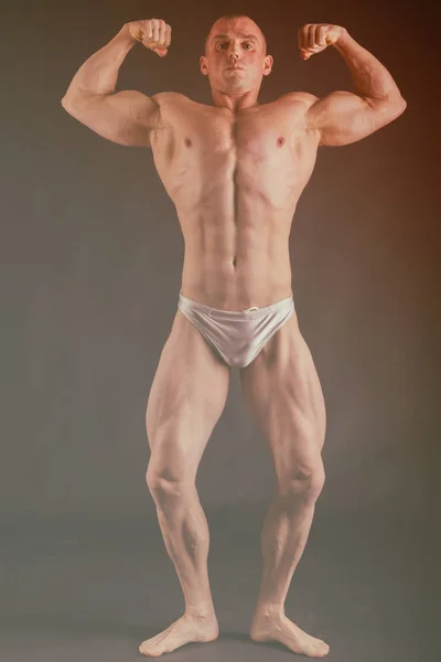 Culturista posando en diferentes poses demostrando sus músculos. Fracaso en un fondo oscuro. Varón mostrando tensión muscular. Hermoso atleta cuerpo muscular . — Foto de Stock