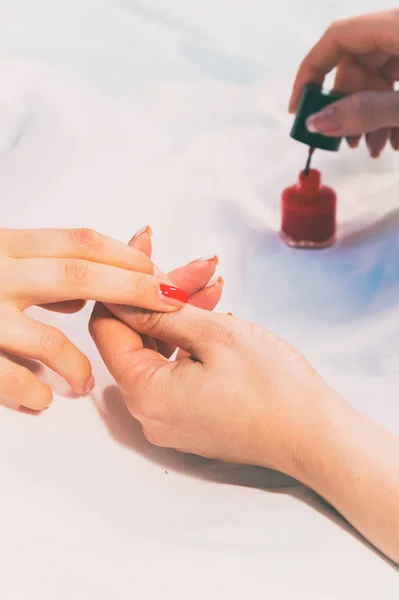 A specialist does a manicure to a girl in a spa salon.