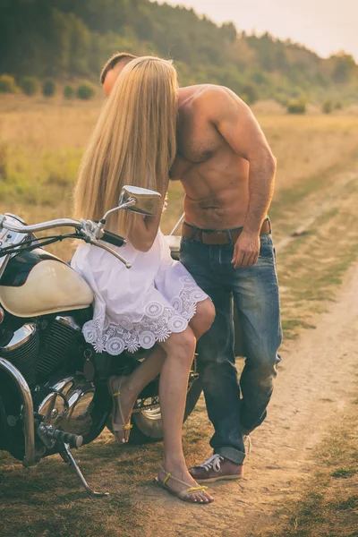 Loving couple on a motorcycle in a field — Stock Photo, Image