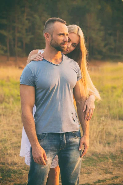 Lovers in a field at sunset — Stock Photo, Image