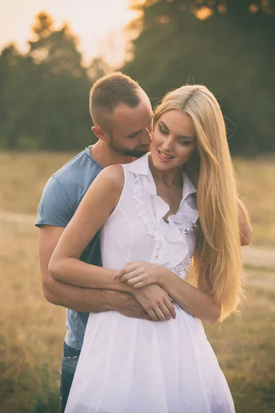 Lovers in a field at sunset — Stock Photo, Image