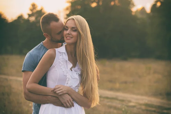 Amantes em um campo ao pôr do sol — Fotografia de Stock