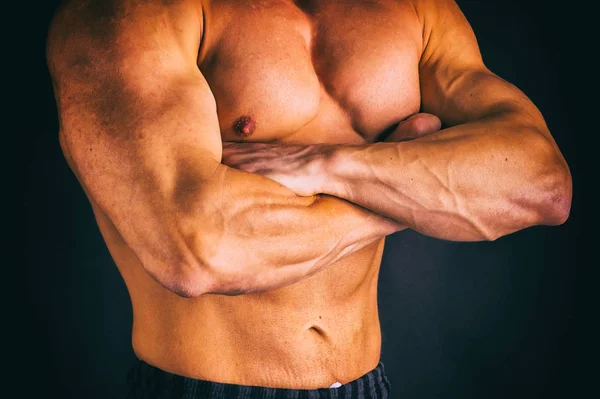 Een man met een schitterende gespierd lichaam op een zwarte achtergrond — Stockfoto