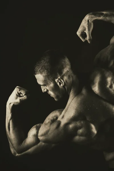 Bodybuilder op een donkere achtergrond. — Stockfoto