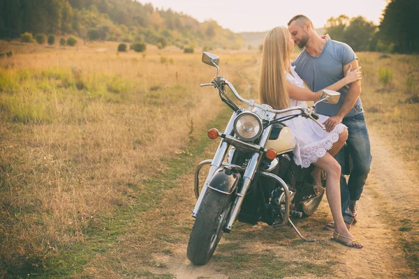 Loving couple on a motorcycle in a field — Stock Photo, Image