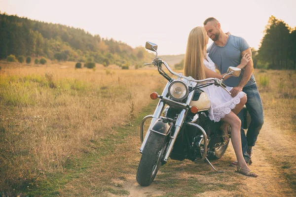 Casal amoroso em uma motocicleta em um campo — Fotografia de Stock